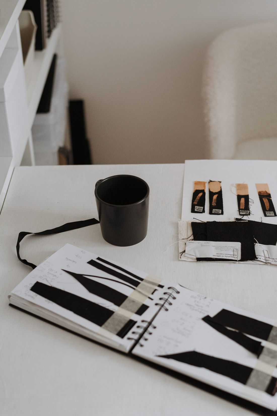 Fabric swatches and a sketchbook on a bright designer desk.