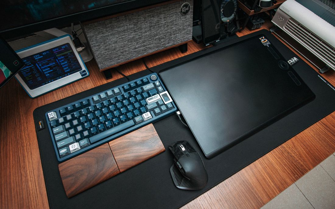 A desk with a drawing tablet, keyboard and computer accessories.