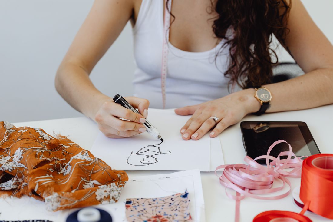 A fashion designer drawing clothing ideas beside fabric samples.
