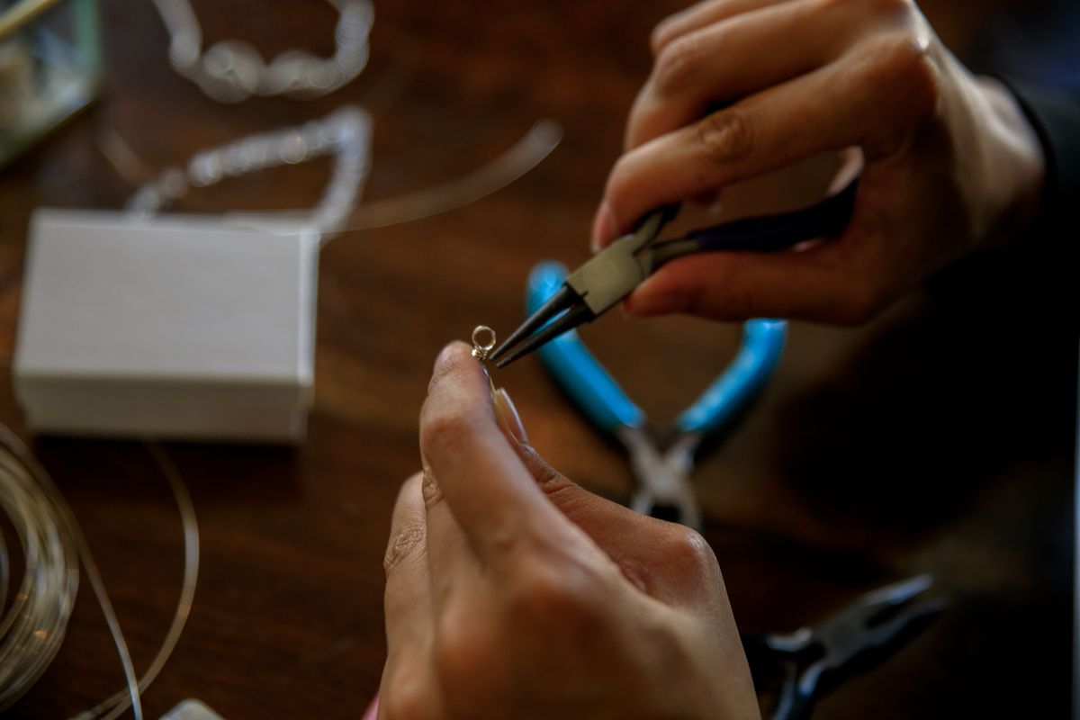 Detailed shot of handcrafting jewelry using pliers, showcasing precise artisan work.