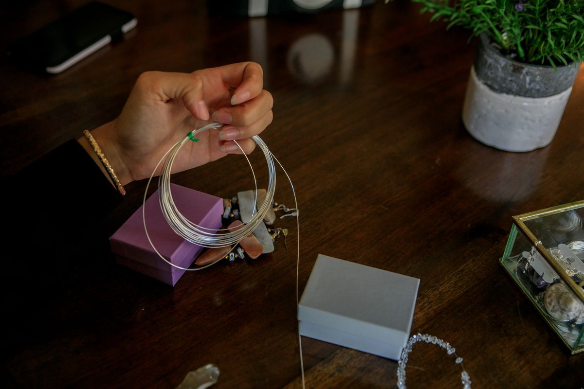 Close-up of hands creating handmade jewelry using wire and beads, showcasing artisan skills and creativity.
