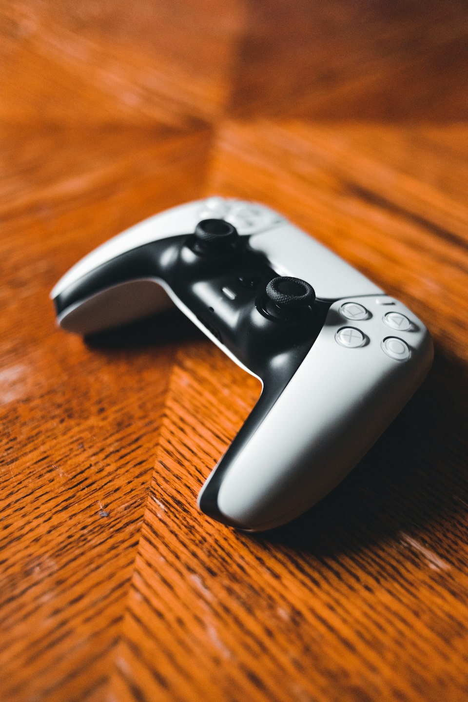 A black and white game controller on a wooden table — editorial illustration