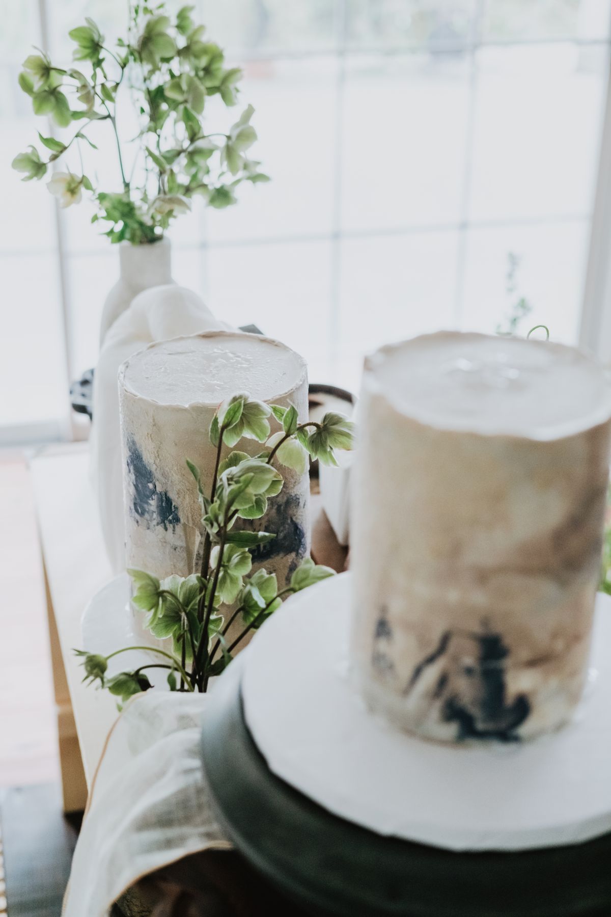 Artistic cakes decorated with lush green plants in a soft, warm ambient setting.