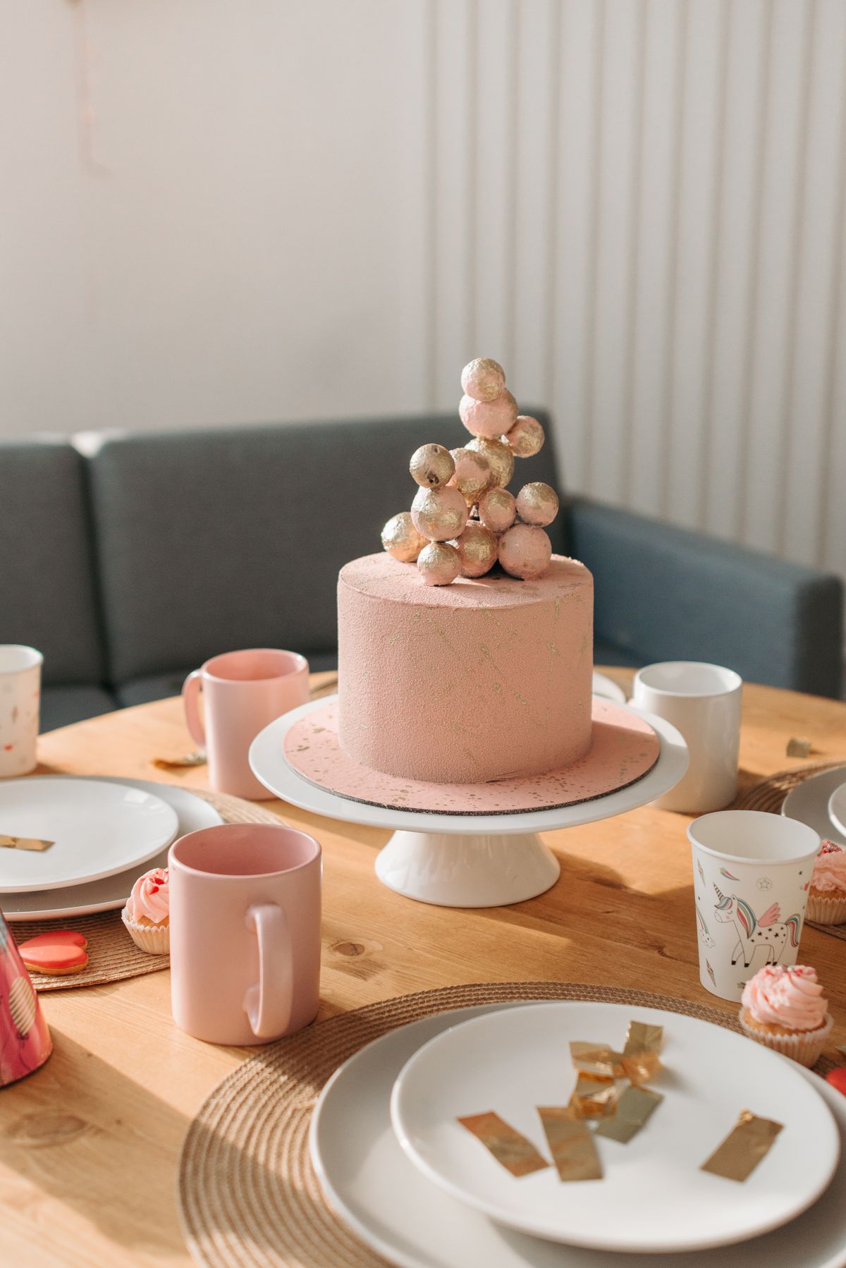 Pink birthday cake with decorations on a dining table set for celebration, featuring elegant party decor.