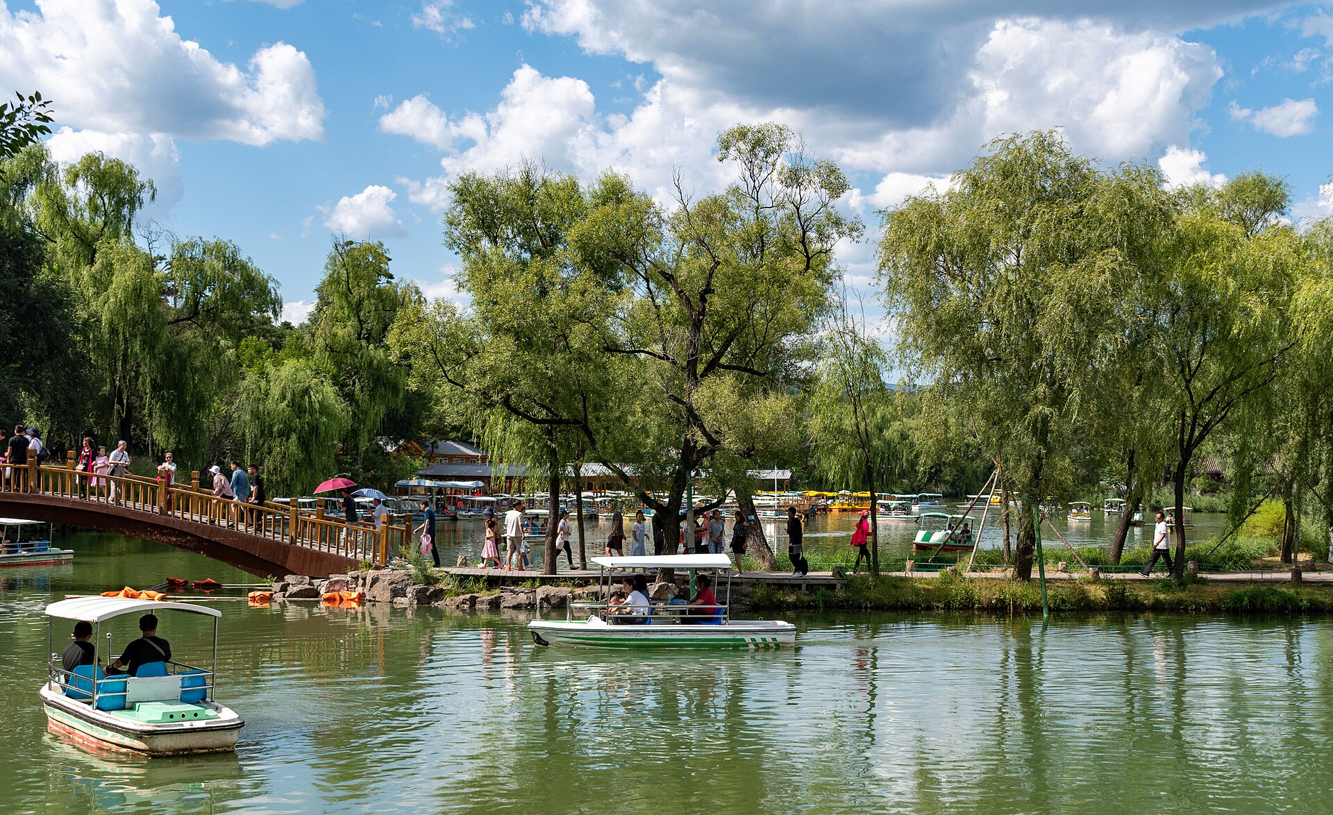 Willows, a pedestrian bridge and boats on a lake inside Chengde Mountain Resort