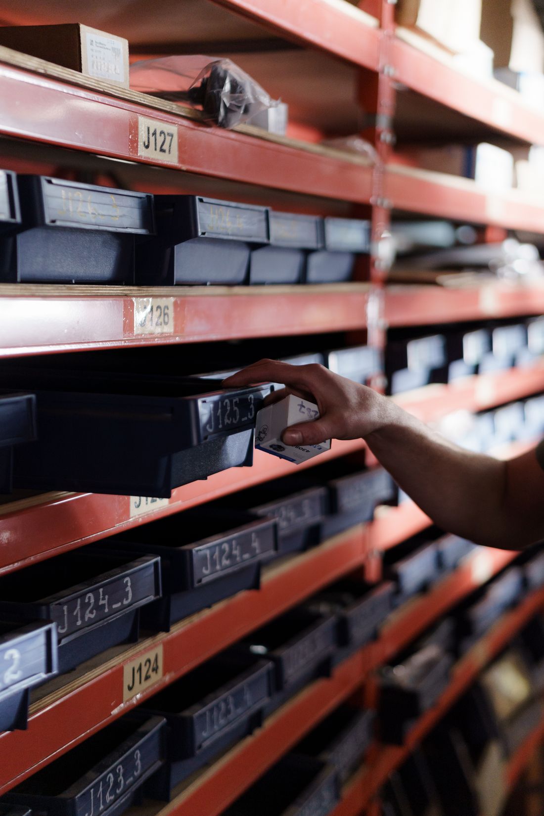 A hand retrieving a storage bin from shelving.