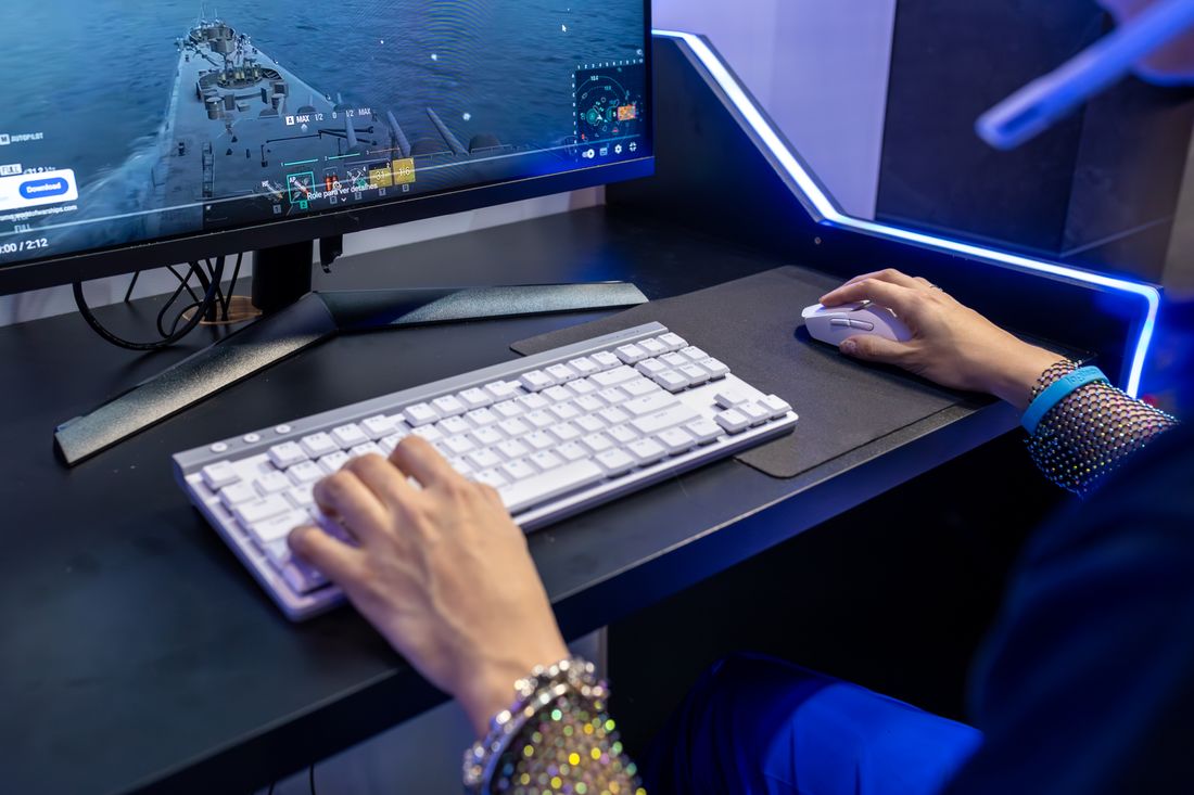 A player using a keyboard and mouse at a gaming computer.