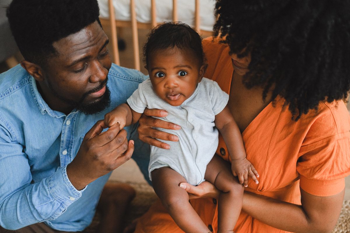 Loving parents holding adorable baby in a warm, intimate home environment.