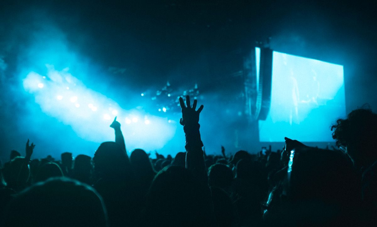 Audience and concert stage under blue night lighting.