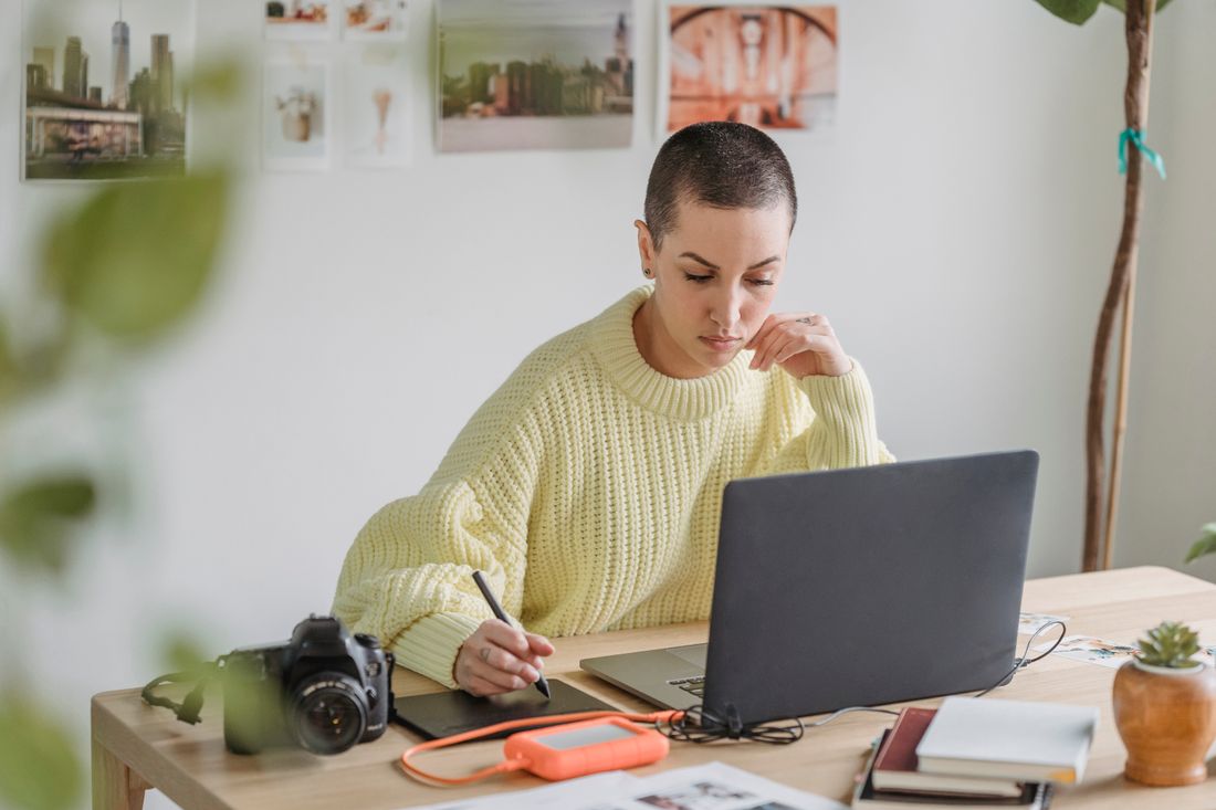 A designer using a drawing tablet beside a laptop.