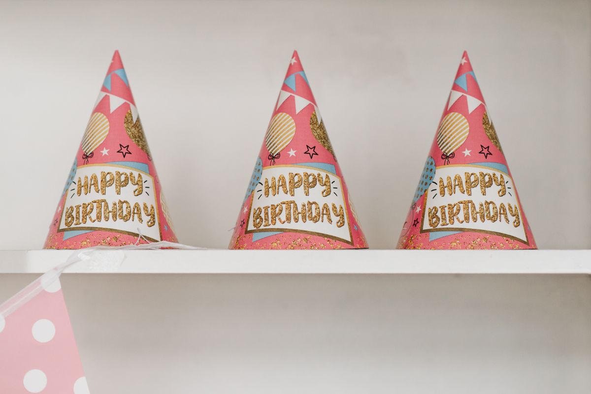 Three colorful birthday party hats on a shelf, celebrating a festive occasion.