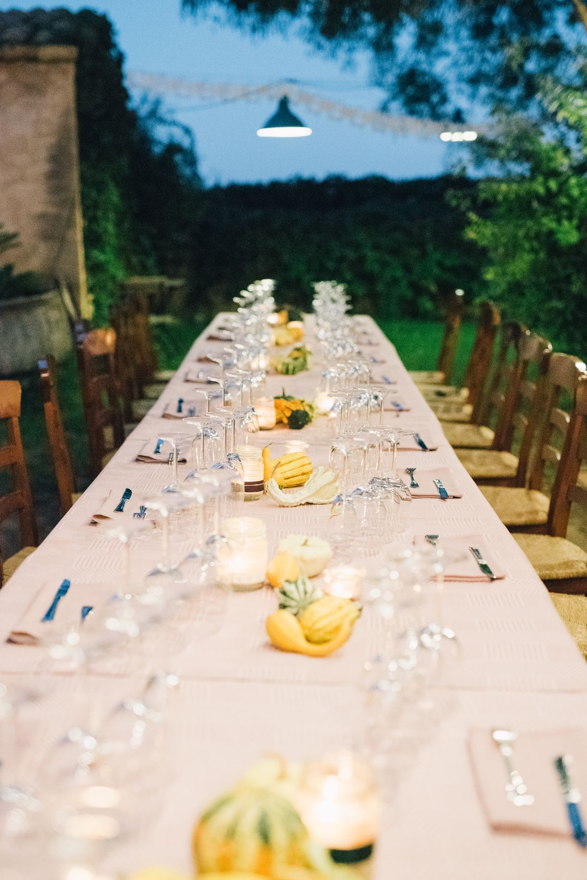 Long outdoor dining table beautifully set with candles and decor, ready for an evening gathering.