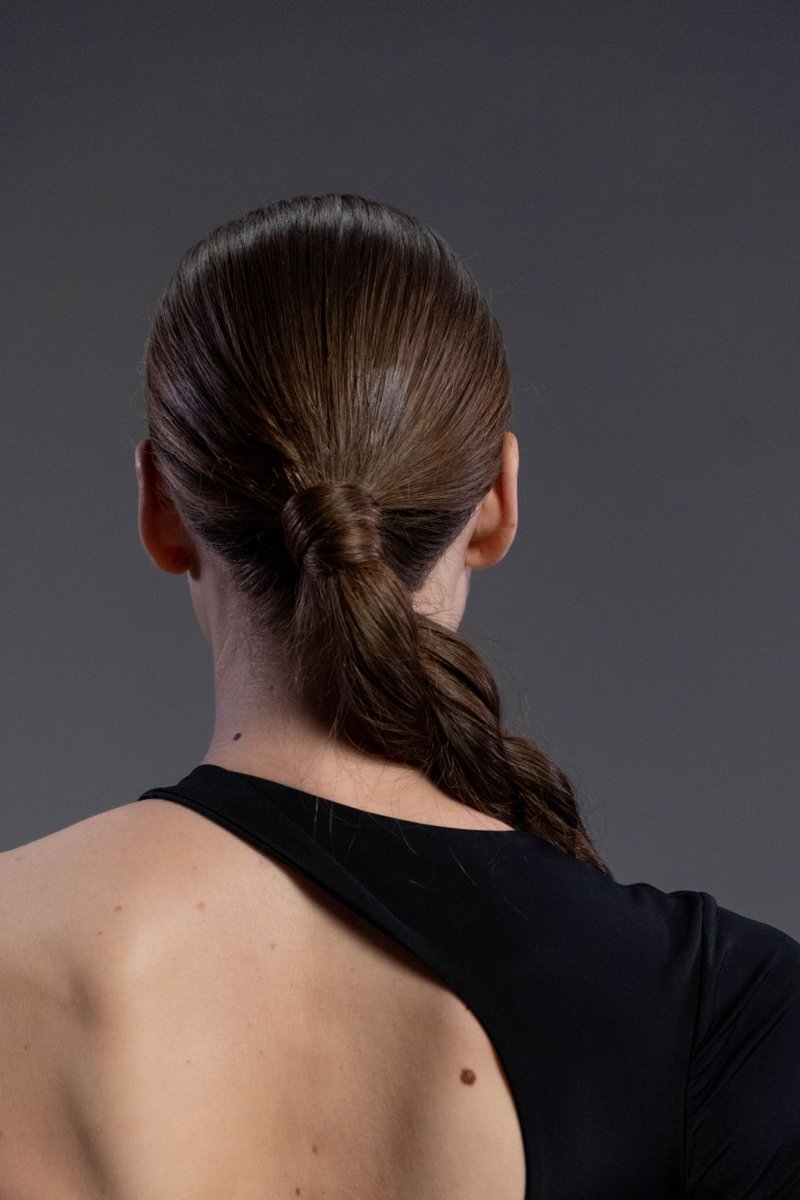 Rear view of a dark-haired woman wearing a ponytail.