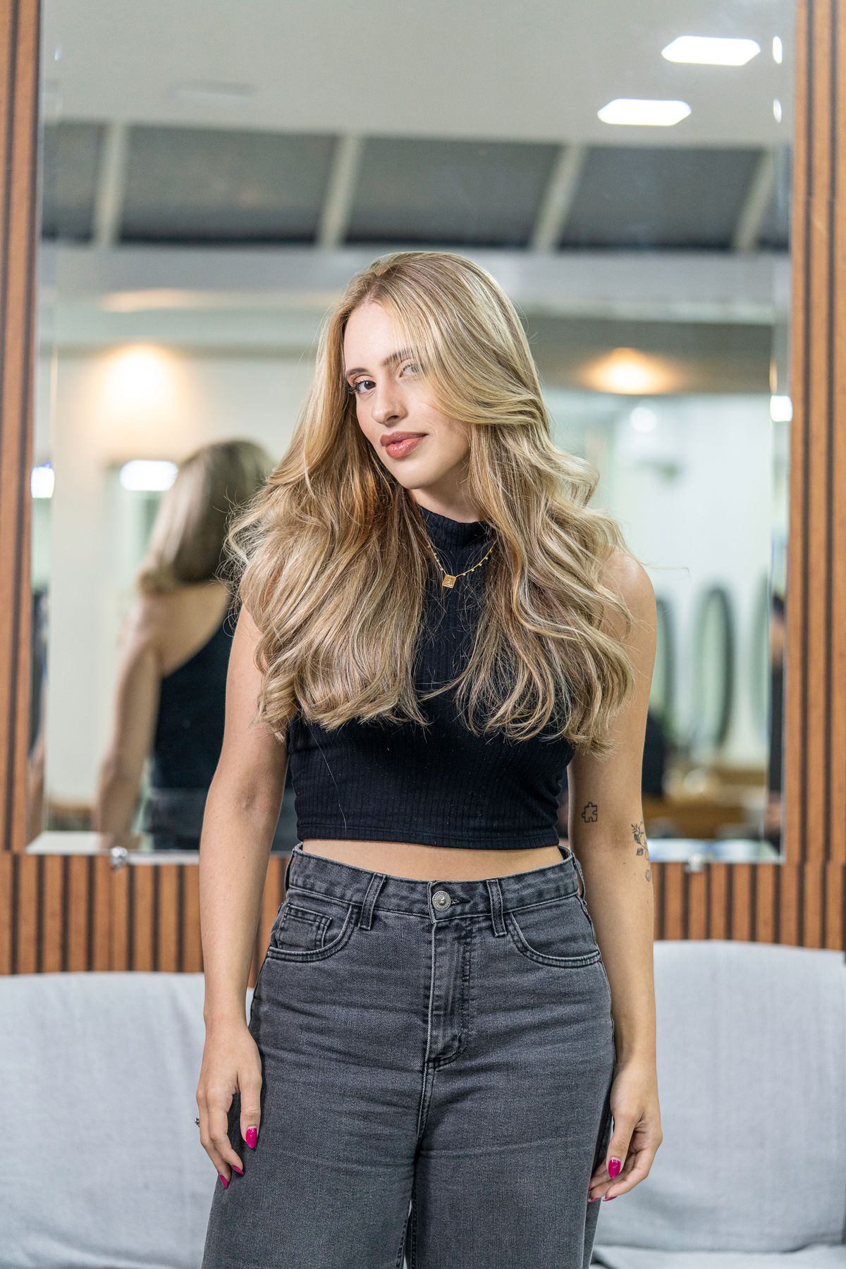 Blonde woman stands confidently in a modern salon, showcasing her elegant hairstyle.