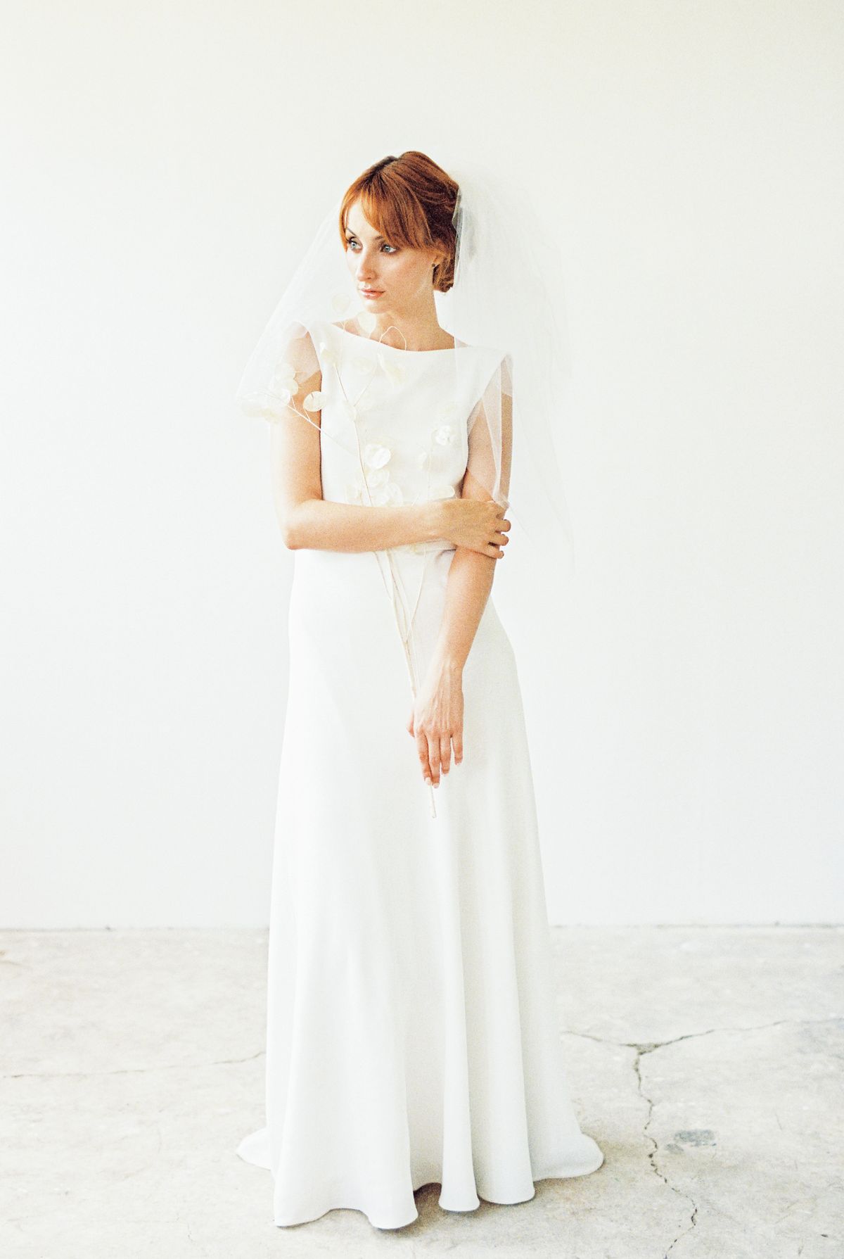 A graceful bride in a sleeveless wedding dress with a veil, showcasing timeless elegance.