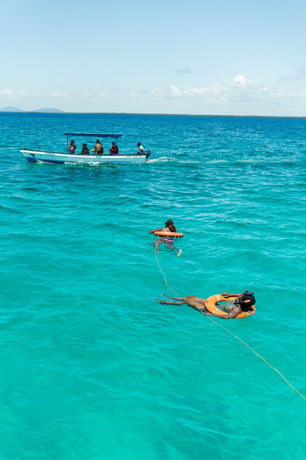 Snorkelers explore vibrant tropical waters near a boat, surrounded by clear blue sea.