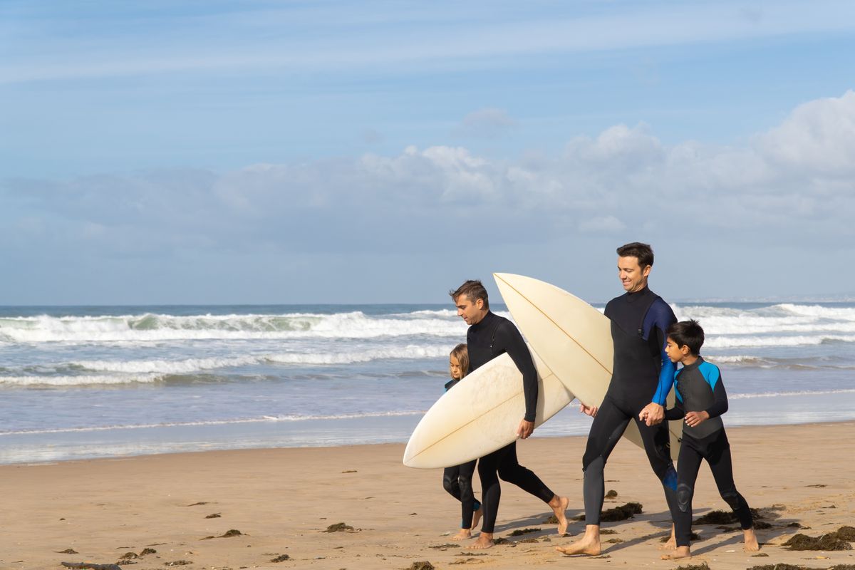 Family enjoying a sunny day surfing on a beautiful beach in Portugal. Adventure and joy in every wave.