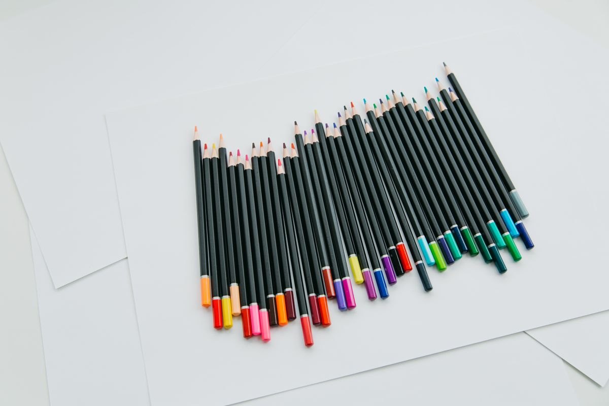 Colored pencils arranged on white sheets of paper.