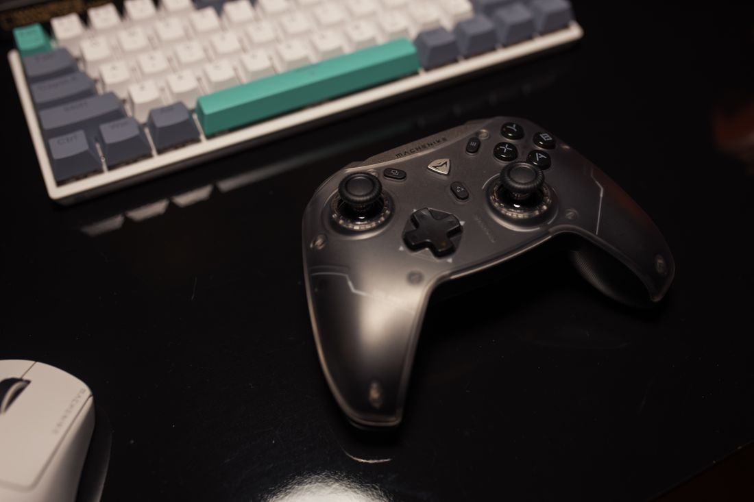 A game controller beside a computer keyboard and mouse.