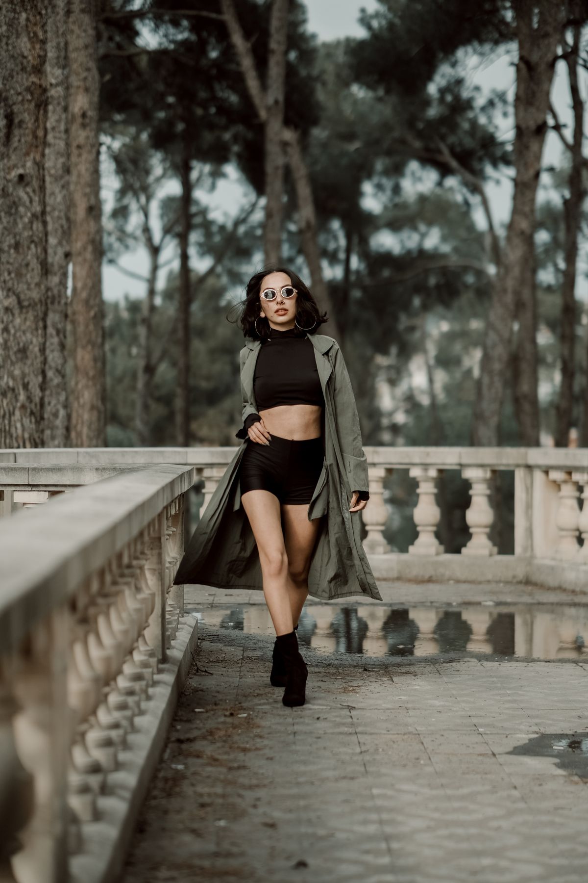 Woman in fashionable attire walking confidently outdoors with sunglasses.