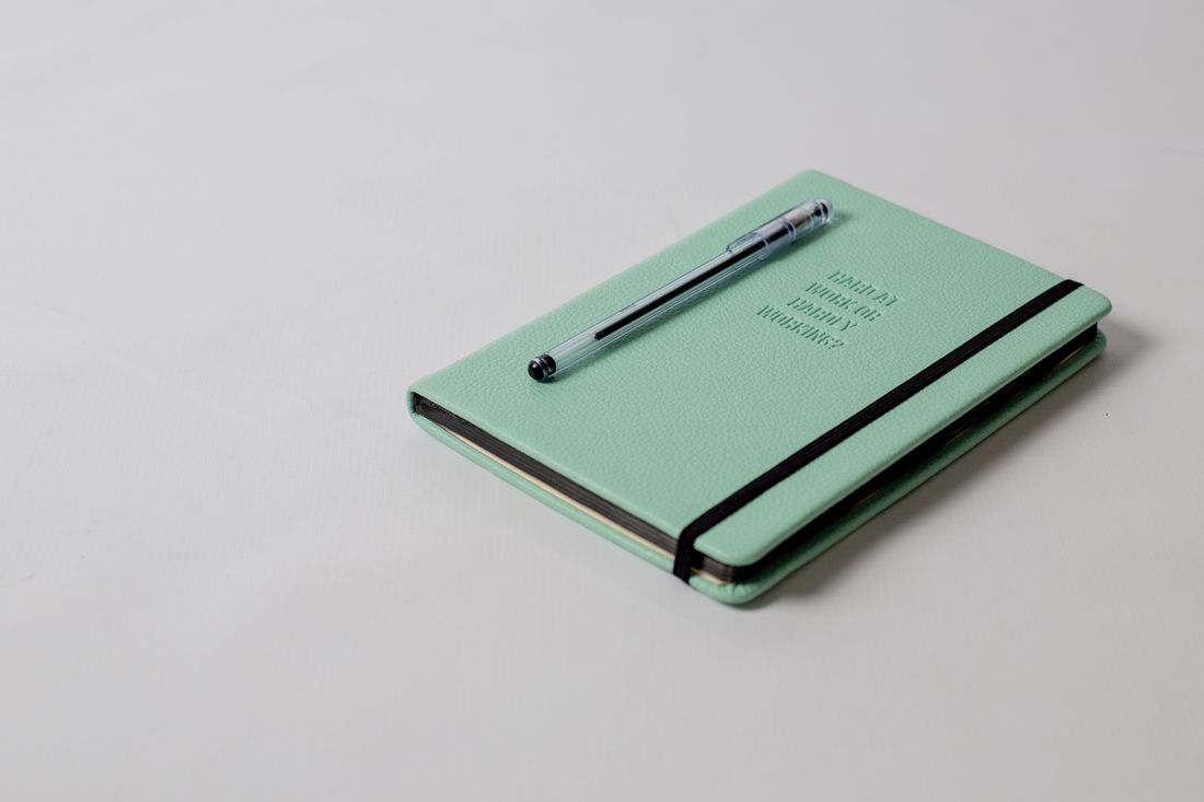 A closed mint notebook with a pen.
