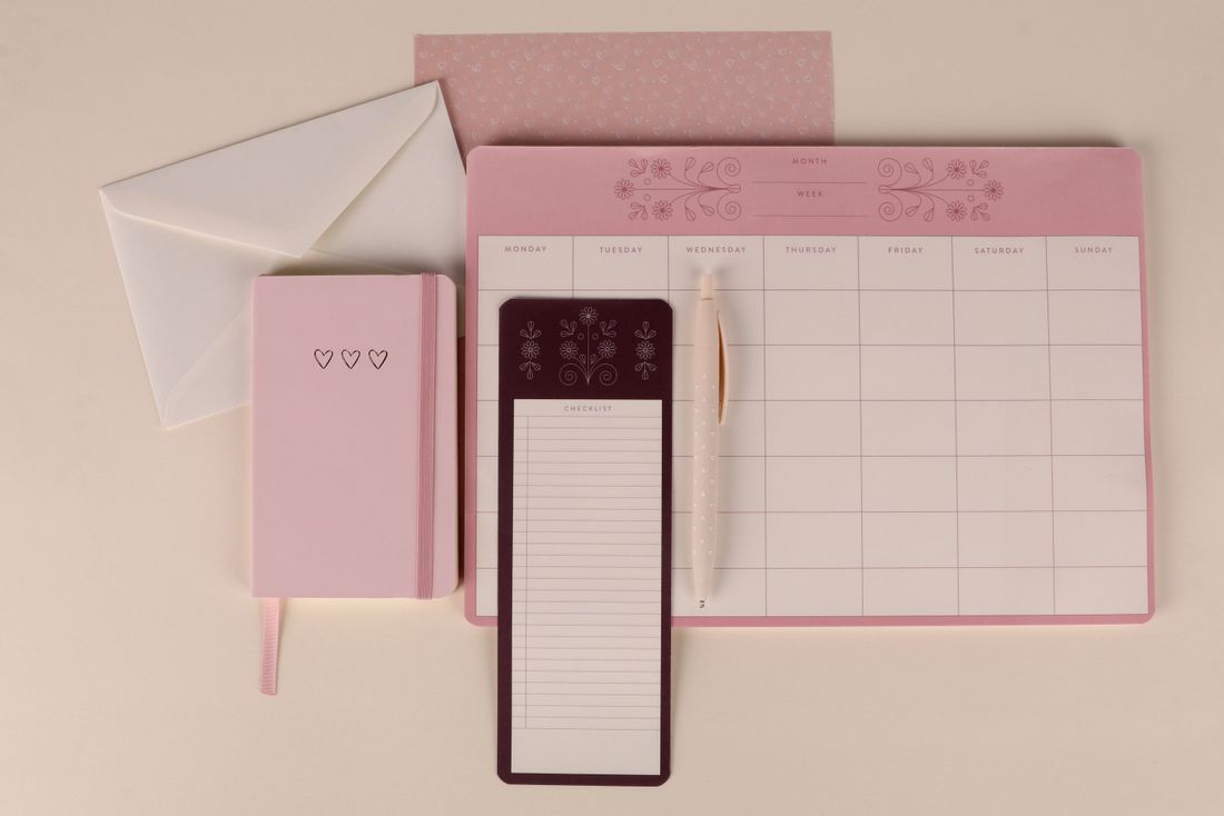 A planner, notebook and checklist pad arranged together.
