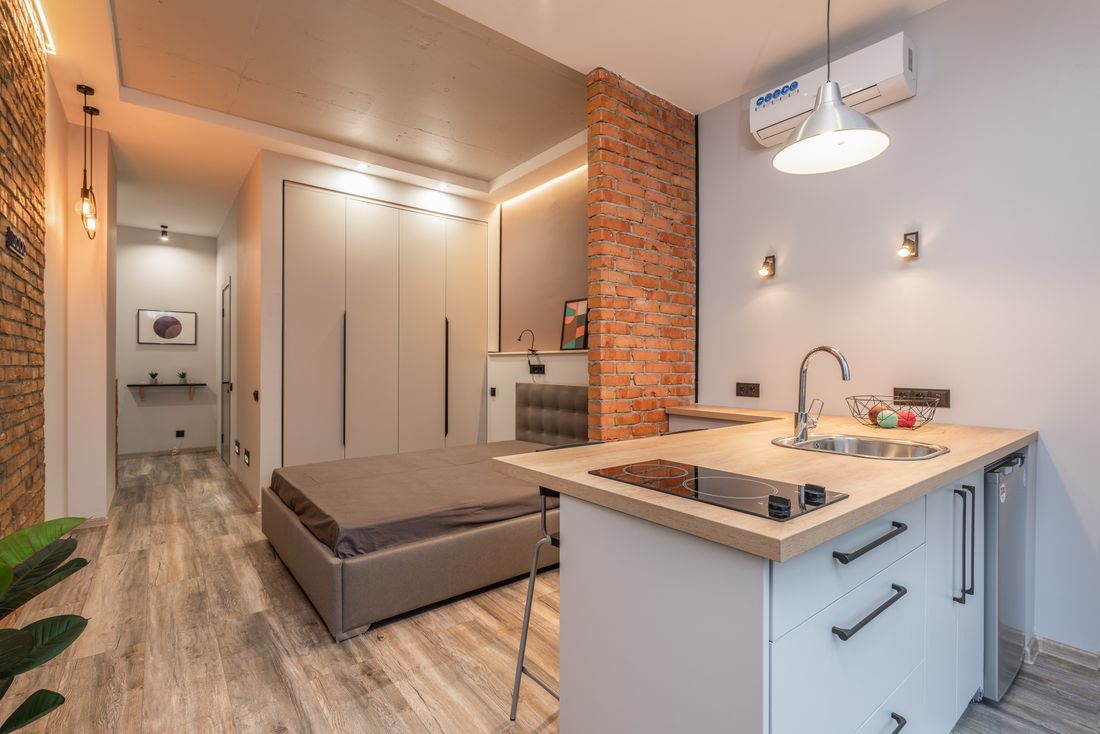 A compact studio with a kitchen and bedroom partition.