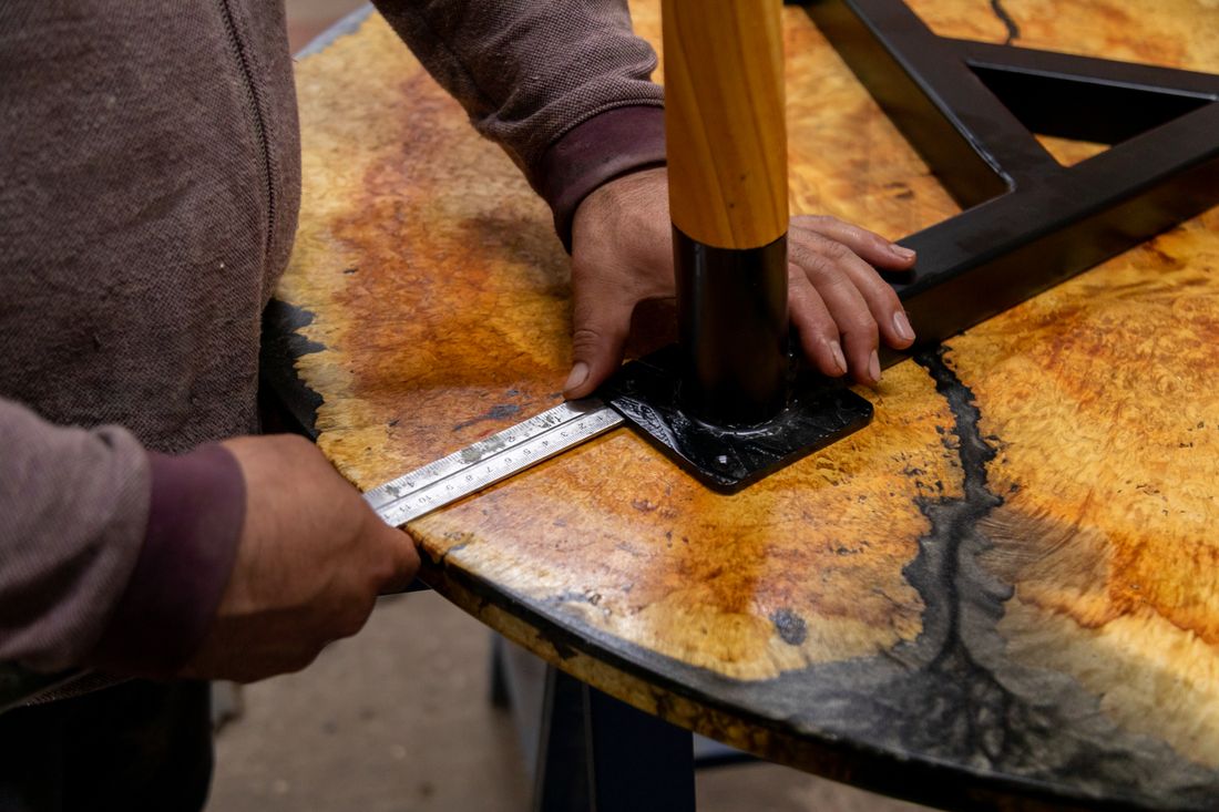 A person measuring a wooden tabletop.