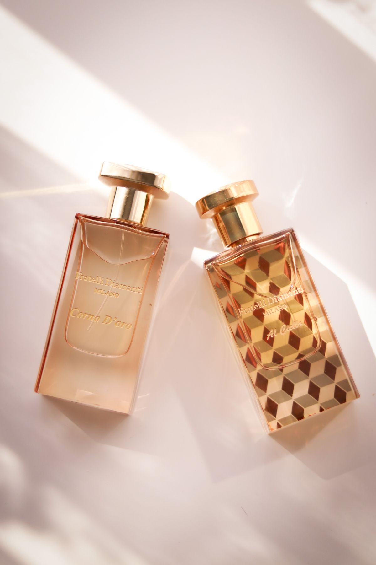Two elegant perfume bottles with geometric designs in a bright setting.