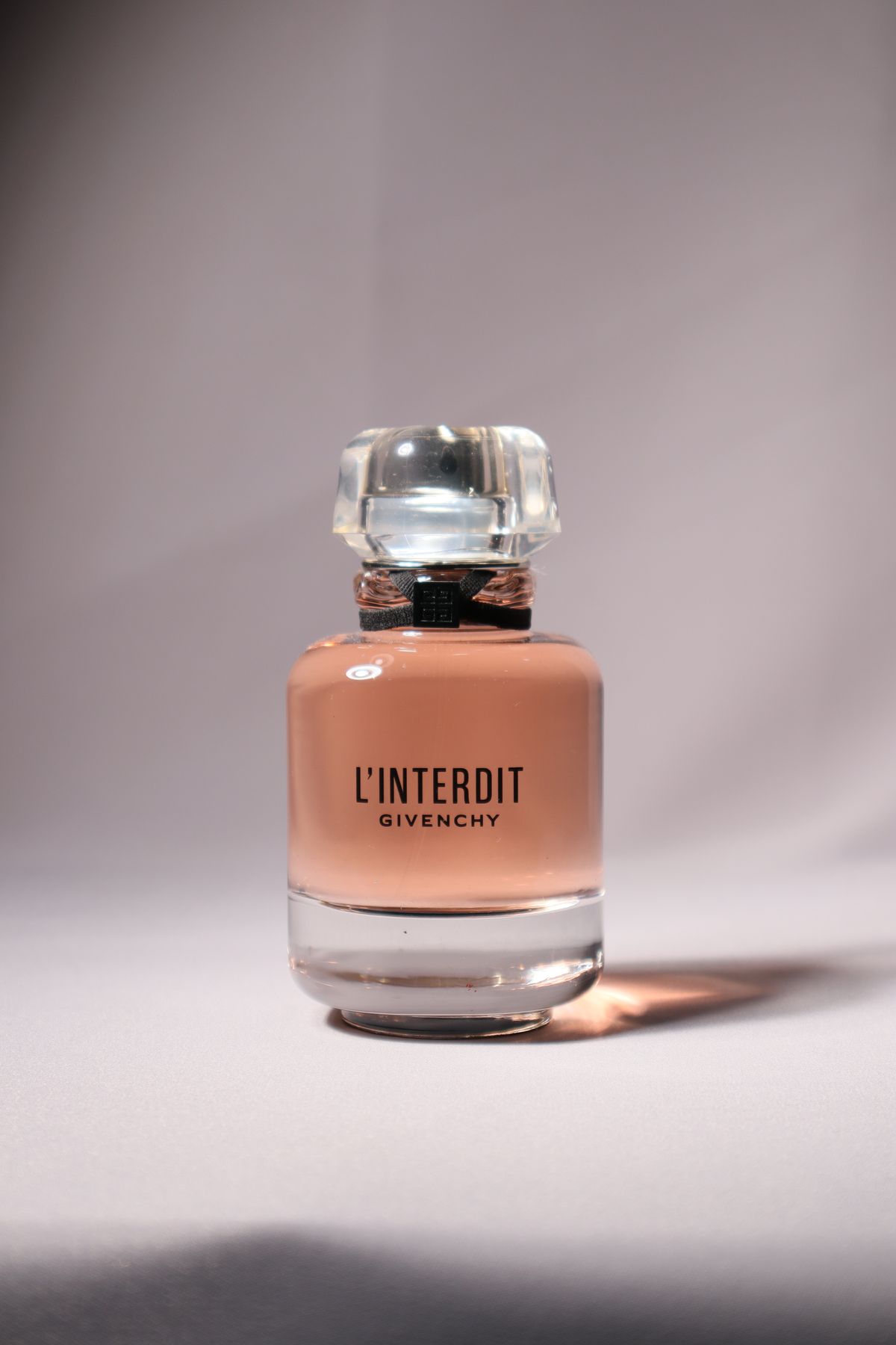 Elegant close-up of a Givenchy L'Interdit perfume bottle on a soft background.
