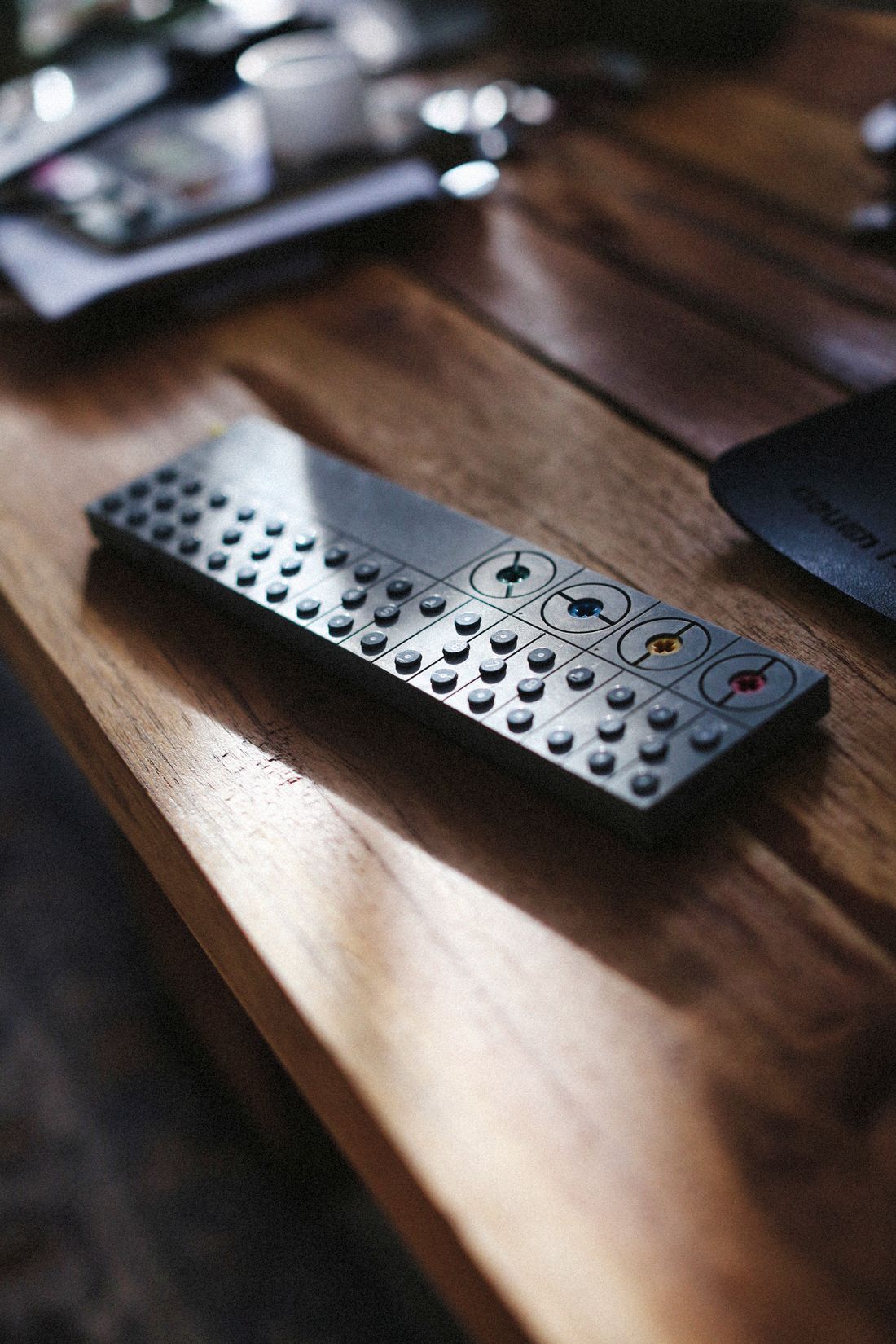 A television remote on a wooden table in natural sunlight.