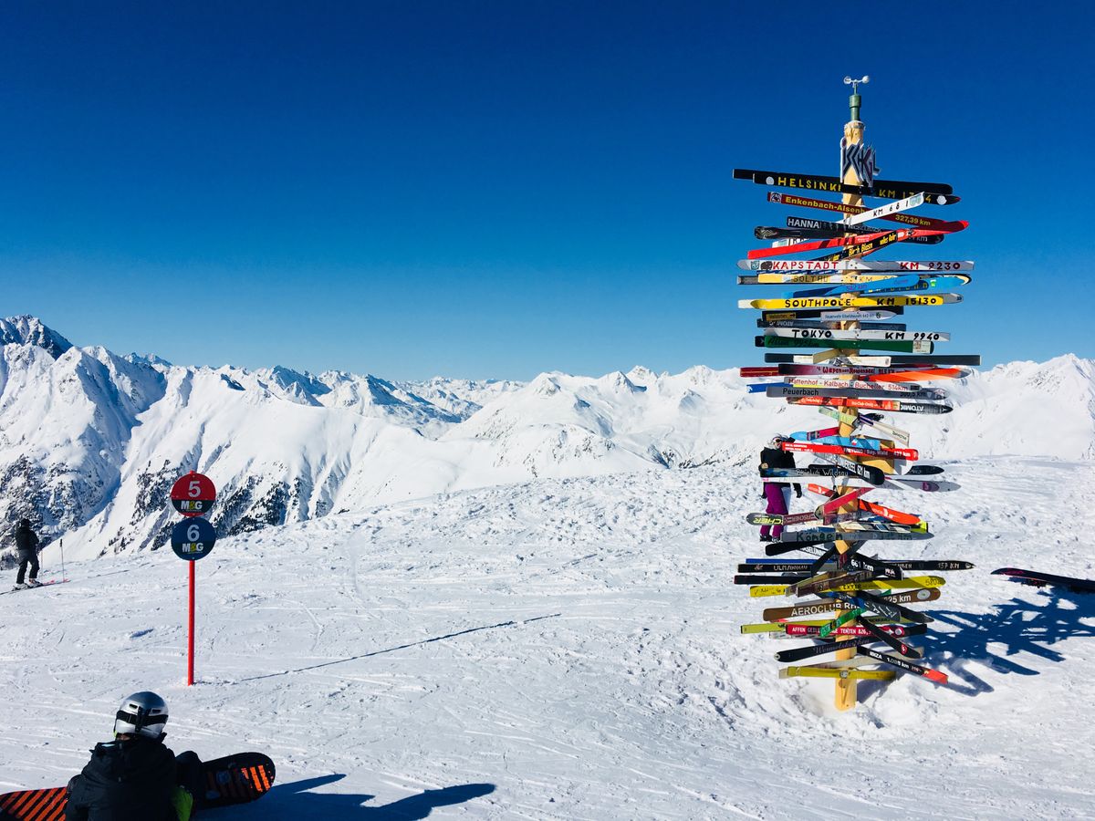 A vibrant ski signpost on a snowy mountain slope with breathtaking alpine views.