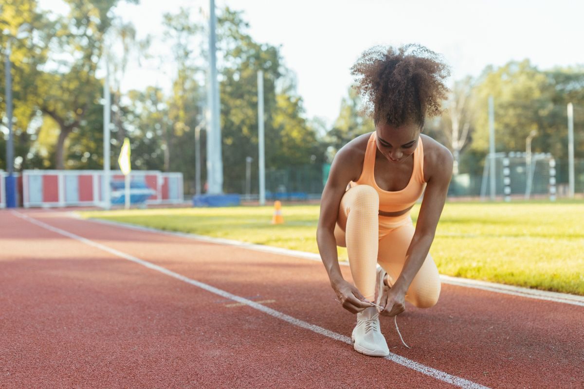 Runner tying shoelaces on an outdoor track.