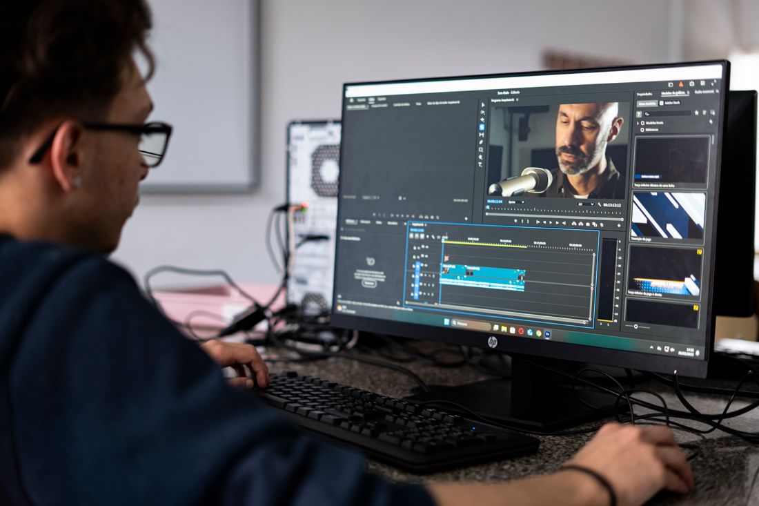A video editor working at a desktop computer in an office.